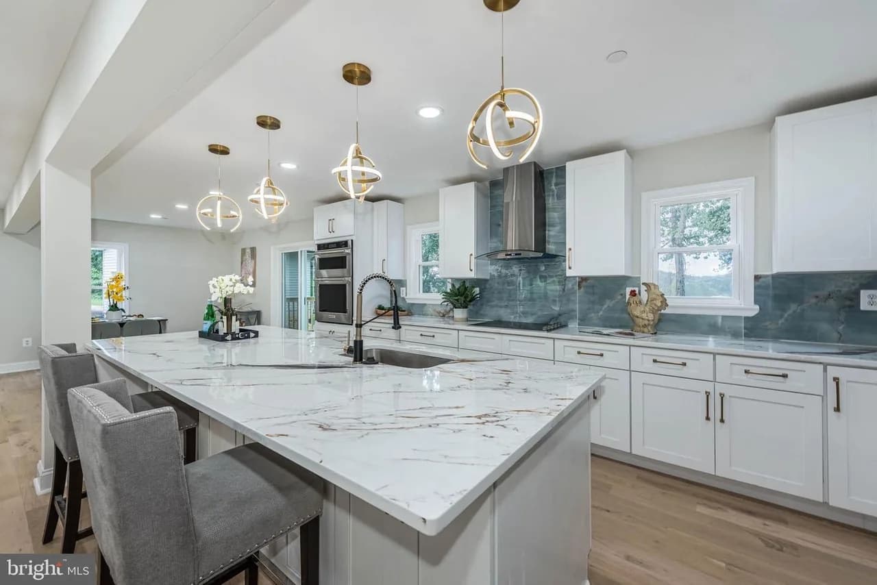 Long Green Pike kitchen with a large white island, curved gold-tone pendant lights and blue-green backsplash
