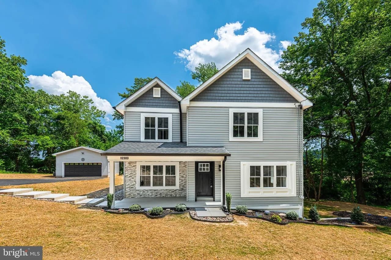 Two-story home at 12303 Long Green Pike with grey siding, a covered front entry and detached garage