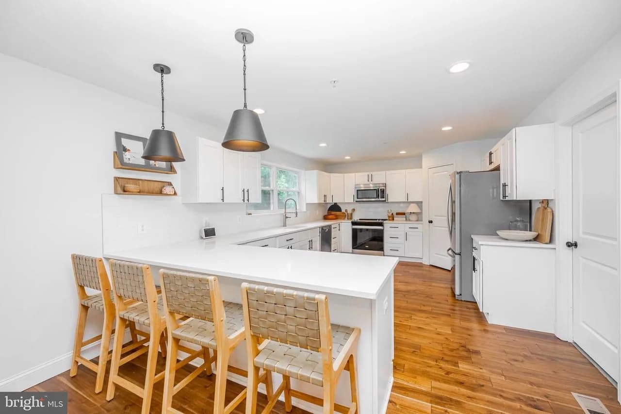 Glenwood kitchen with a seating peninsula, white cabinets and dark pendant lights