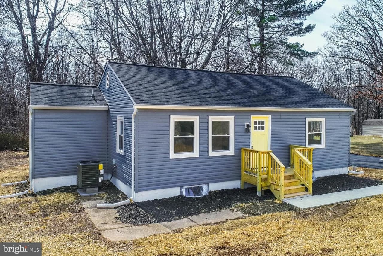 Blue-grey rancher at 731 Walters Mill Road with a yellow entry and trees behind it
